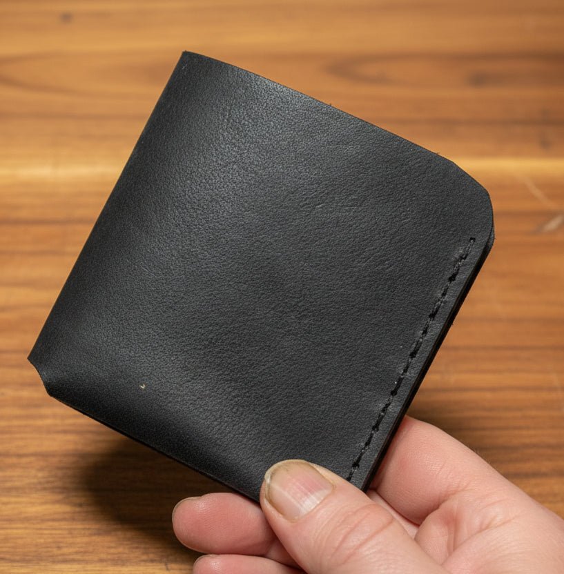 Alt Tag: Compact Bi-Fold Wallet handmade in Black premium leather bi-fold wallet held in hand, slim minimalist design