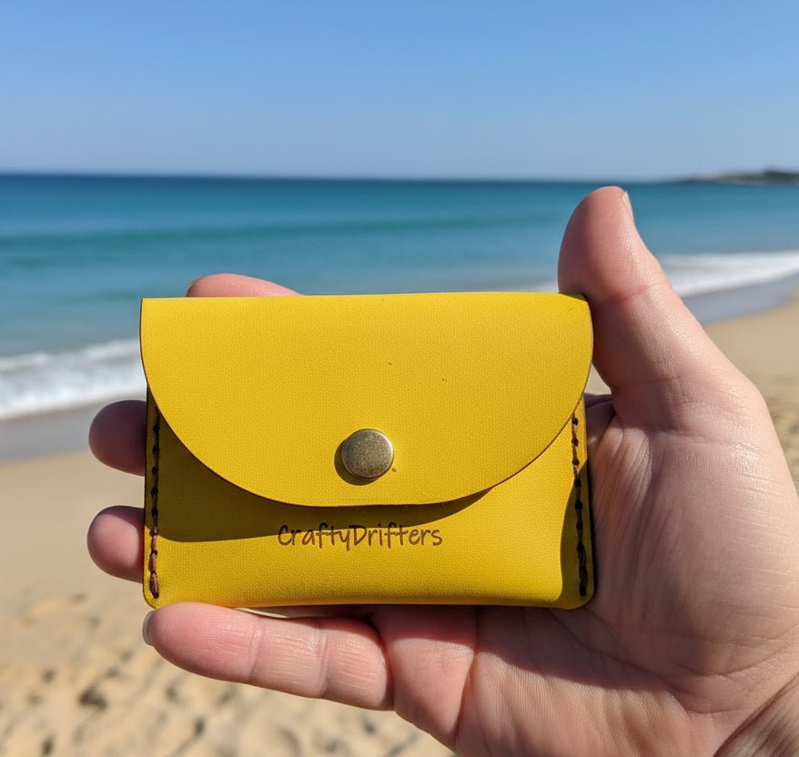 Alt Tag: Handmade leather card - cash wallet in yellow full-grain leather with press-stud flap, held in hand on beach
