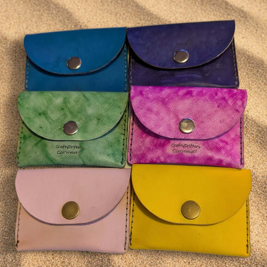 Colorful hand dyed leather coin purses displayed in a stylish arrangement for cash and cards.