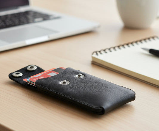 Leather slimline Cardholder with thumb hole displayed on a desk with laptop and notepad.