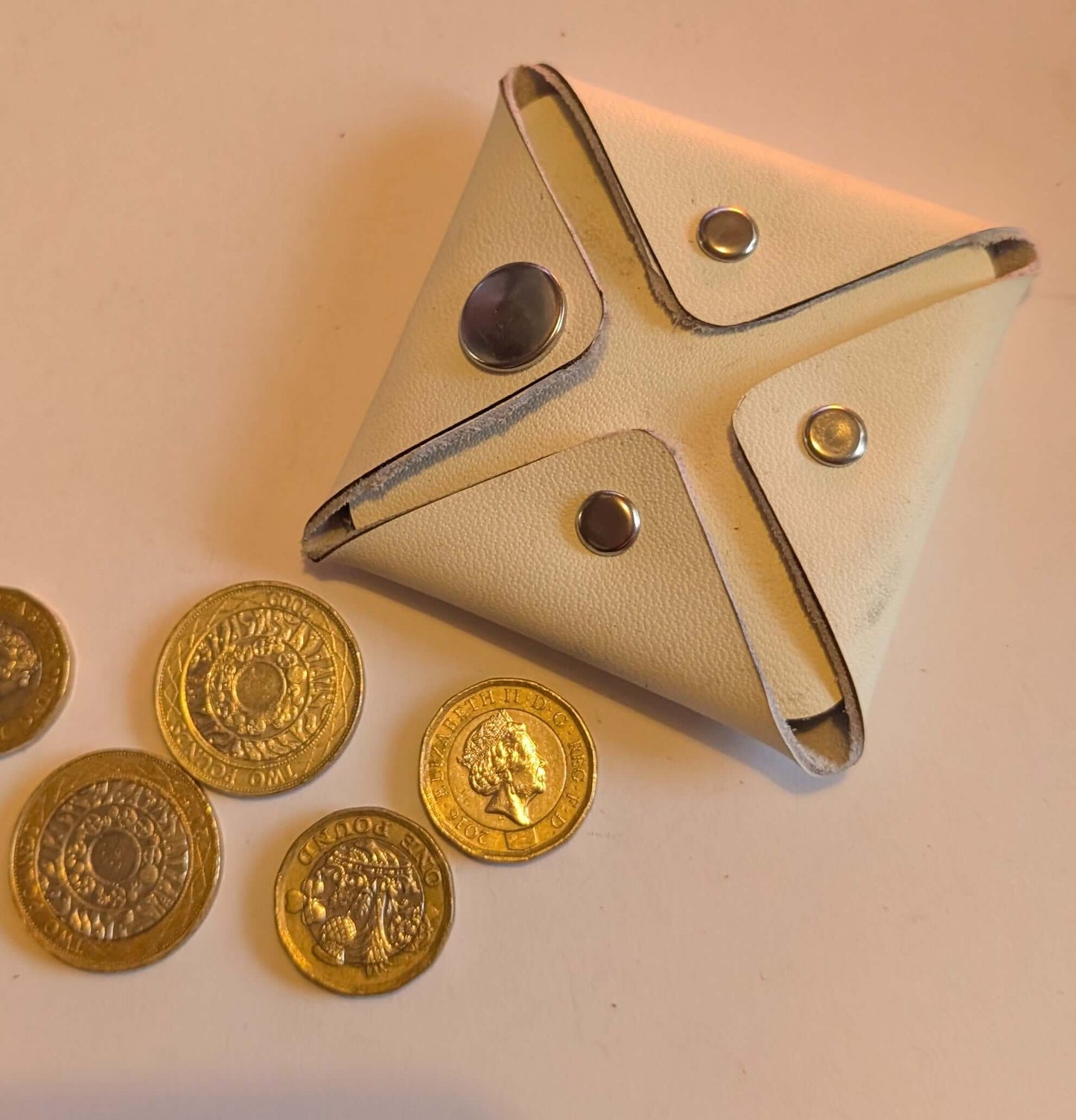 Stitch Free Leather Coin Purse with coins beside it on a light background.